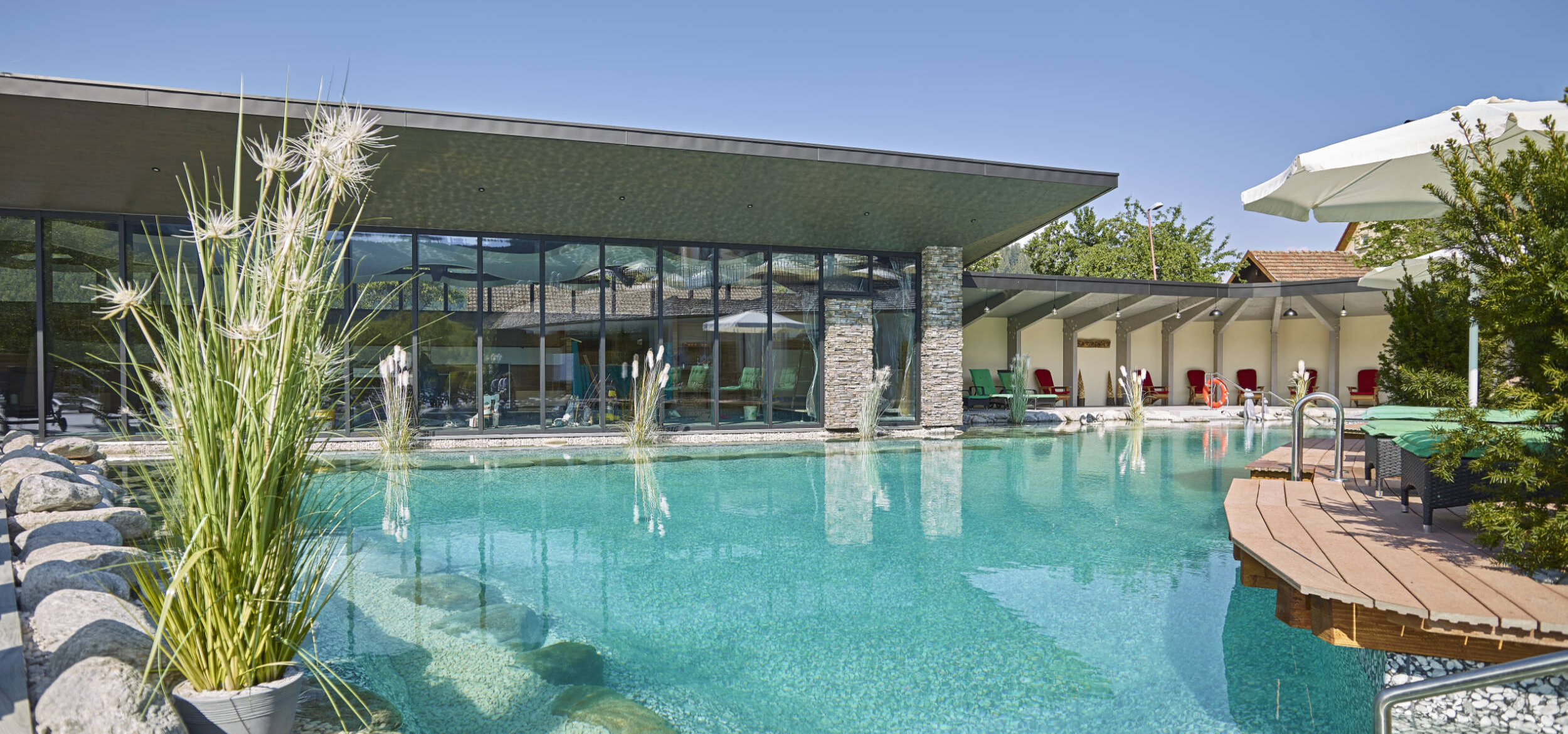 Großer Schwimmteich mit Balena-System mit Bepflanzung im Wellnesshotel „Heselbacher Hof” in Baiersbronn, im Hintergrund das Hotel