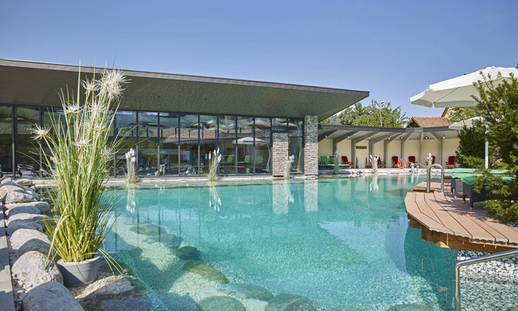 Großer Schwimmteich mit Balena-System mit Bepflanzung im Wellnesshotel „Heselbacher Hof” in Baiersbronn, im Hintergrund das Hotel