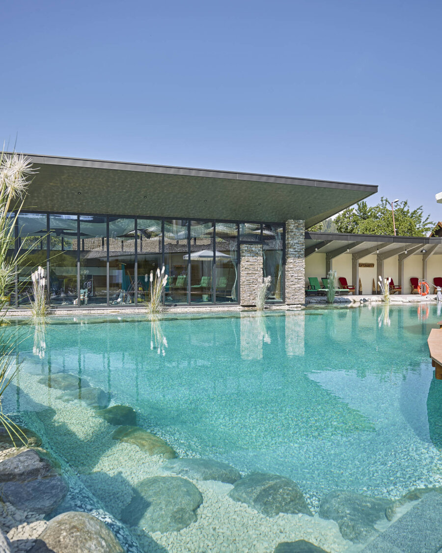 Großer Schwimmteich mit Balena-System mit Bepflanzung im Wellnesshotel „Heselbacher Hof” in Baiersbronn, im Hintergrund das Hotel