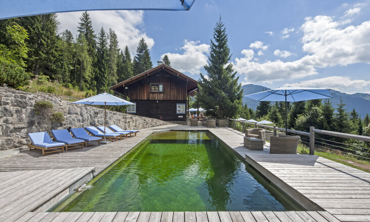 Naturpool mit Balena-System mit Liegen des Hotelbad „Silberghaus” in Bayrischzell, im Hintergrund die Alpen