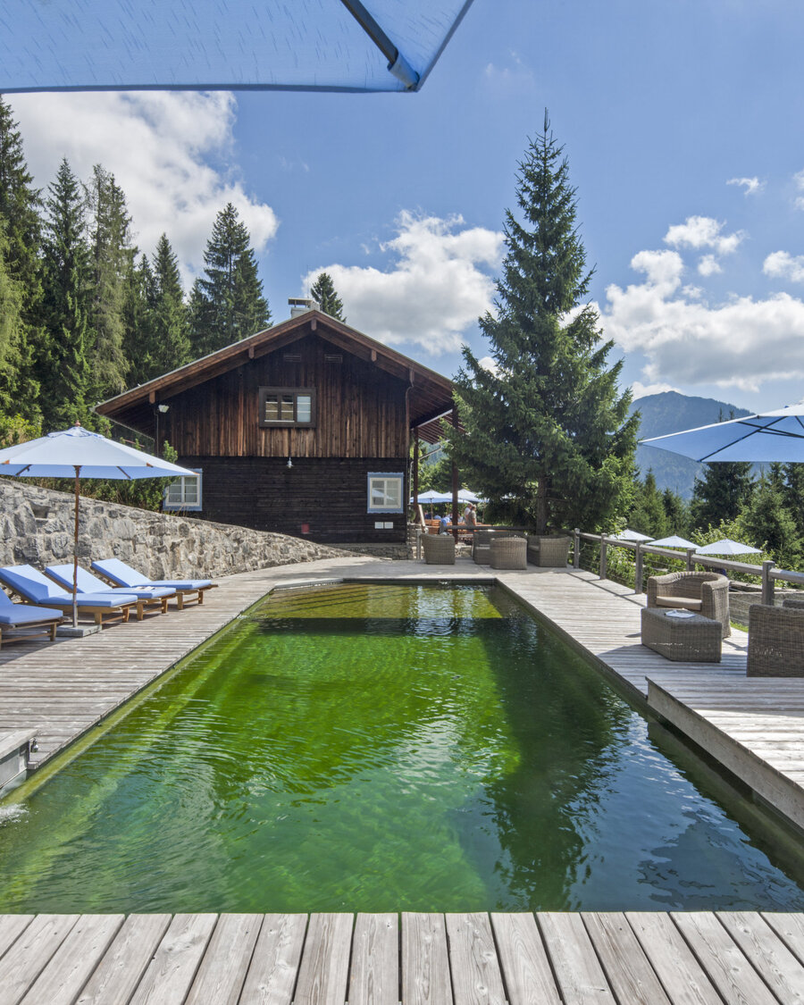 Naturpool mit Balena-System mit Liegen des Hotelbad „Silberghaus” in Bayrischzell, im Hintergrund die Alpen