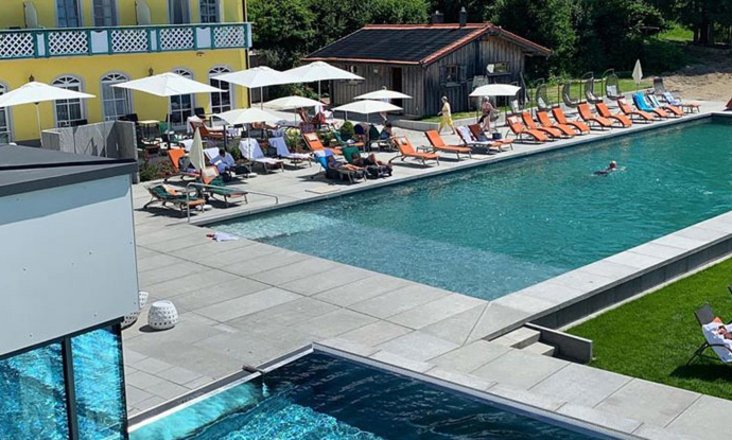 Naturpool mit Balena-System mit Liegen und Gästen im Sport- und Wellness­hotel „Angerhof” in St. Englmar