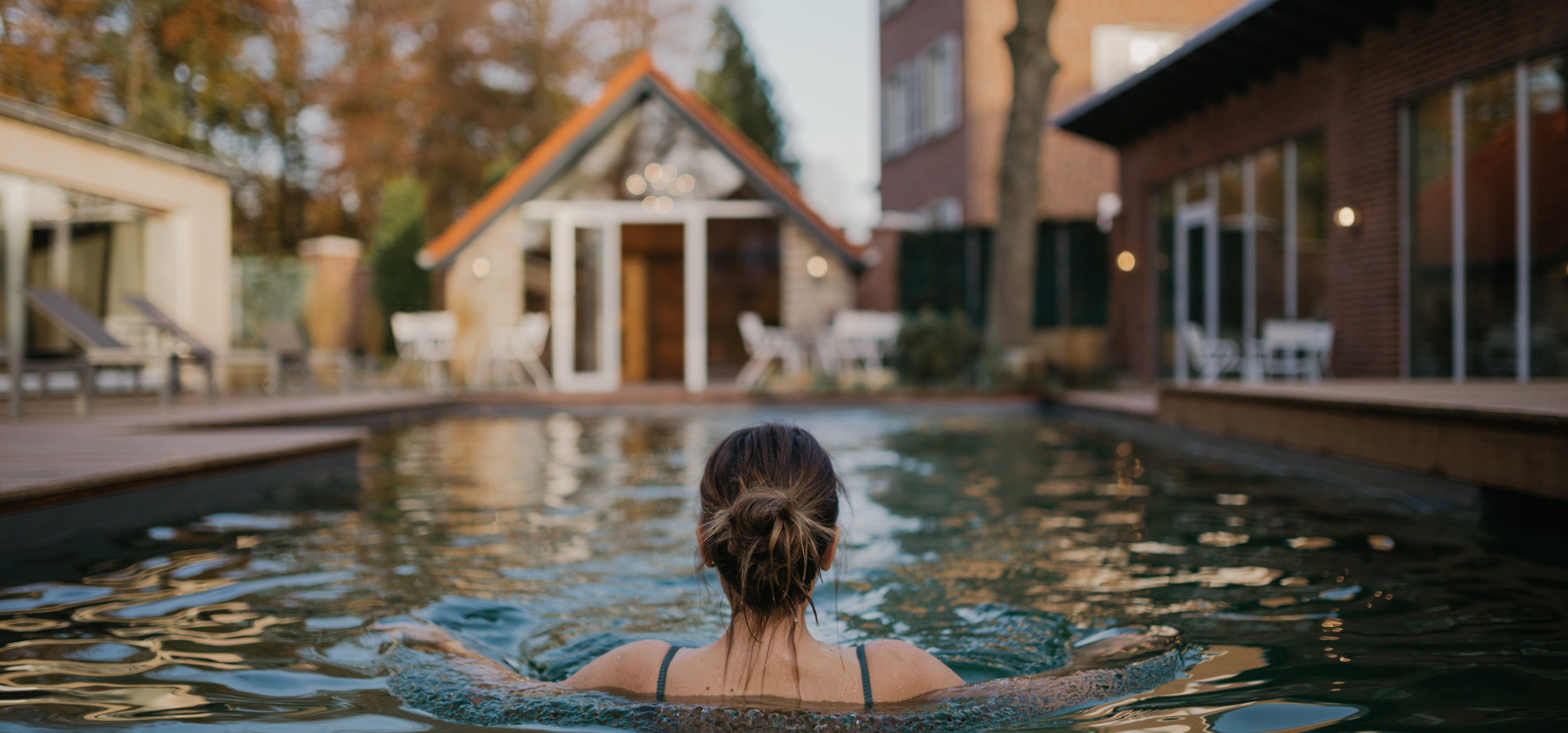 Eine Frau badet im Schwimmbecken des Hotel-Residence „Klosterpforte” in Marienfeld, im Hintergrund angrenzende Gebäude