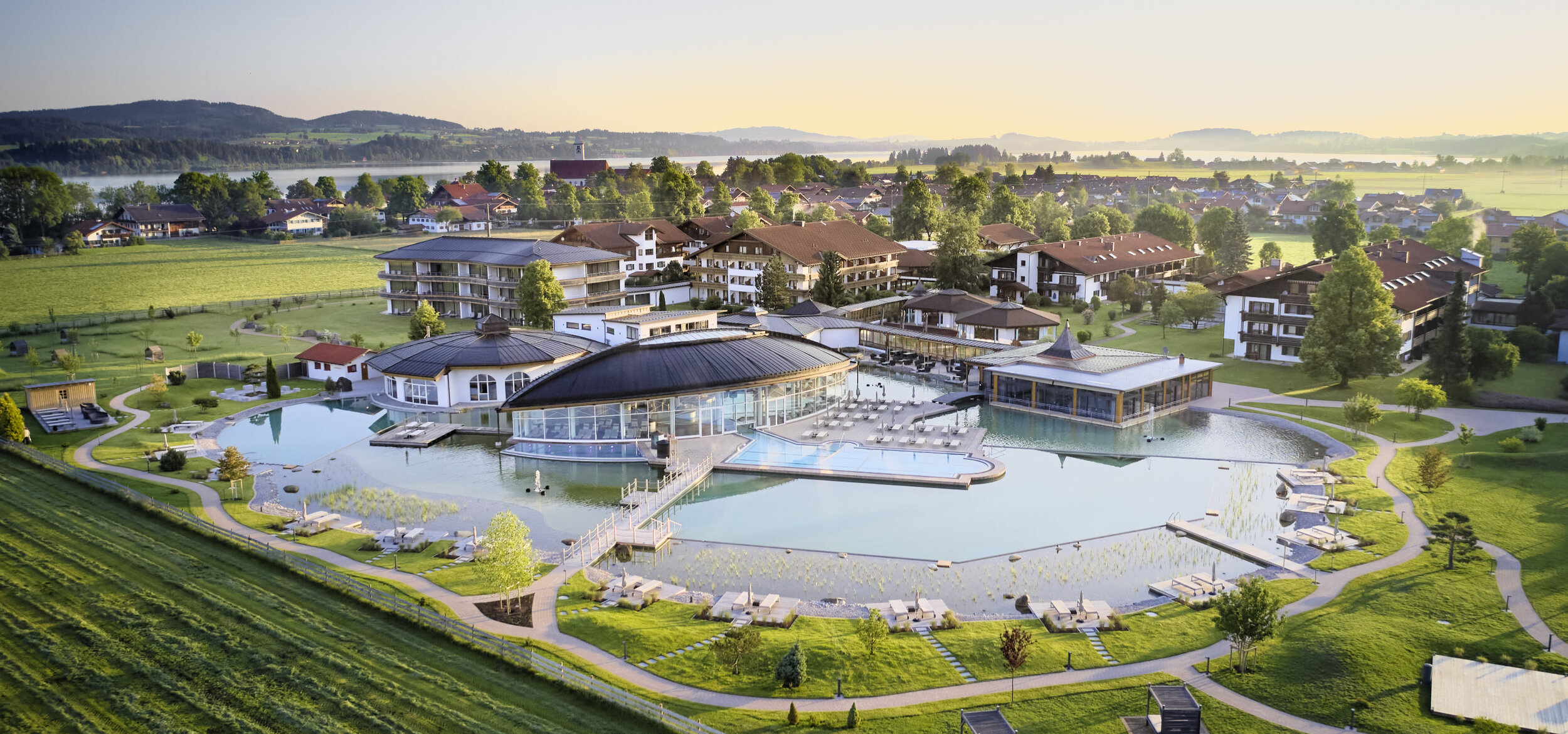 Das „König Ludwig” Wellness & SPA Resort Allgäu in Schwangau aus der Luft fotografiert, im Hintergrund Berge und ein See