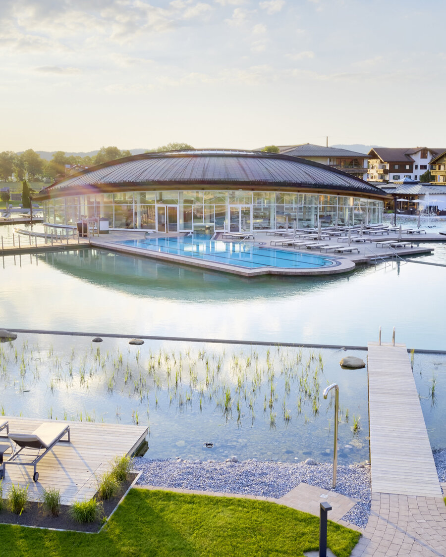 Die Poollandschaft mit Balena-System des „König Ludwig” Wellness & SPA Resort mit Badeliegen und Bepflanzung