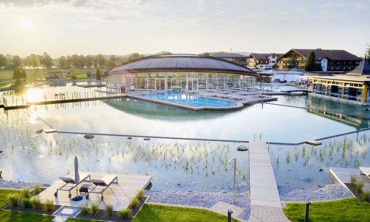 Die Poollandschaft mit Balena-System des „König Ludwig” Wellness & SPA Resort mit Badeliegen und Bepflanzung