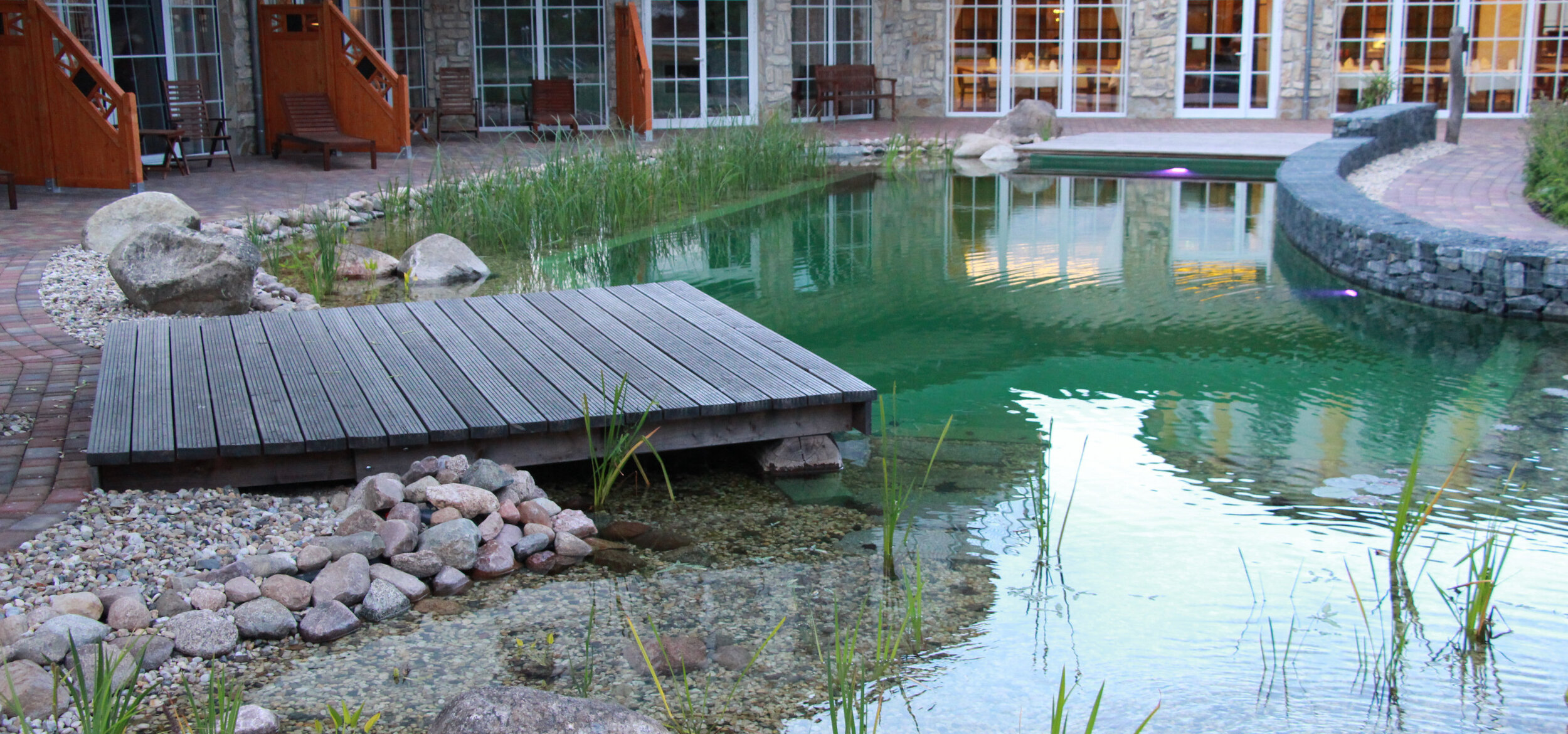 Schwimmteich mit Balena-System mit Liege und Uferbepflanzung im Wellnesshotel SPA & Naturresort „Seeschlösschen” in Senftenberg